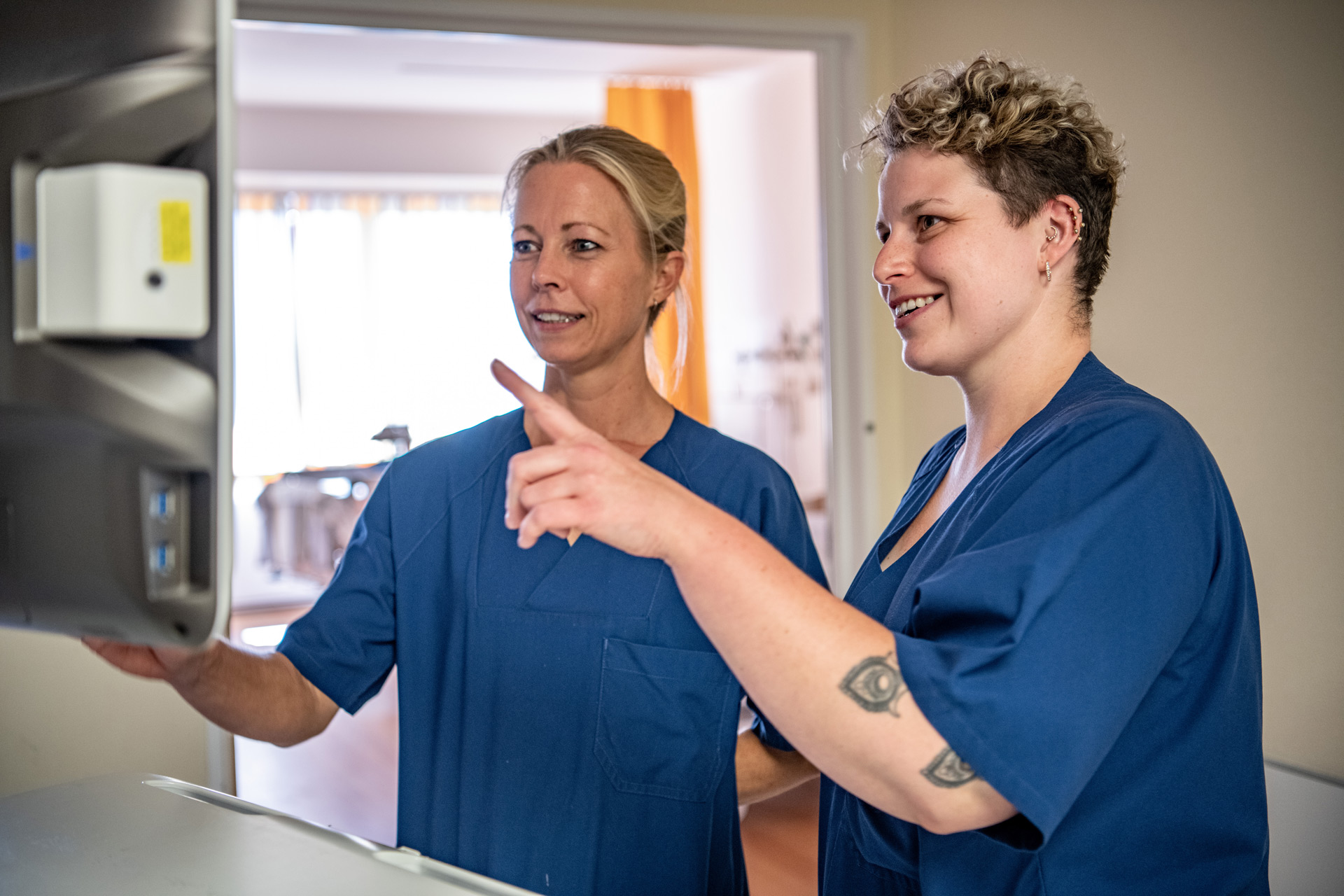 zwei Krankenpflegerinnen sehen sich etwas auf einem Bildschirm an